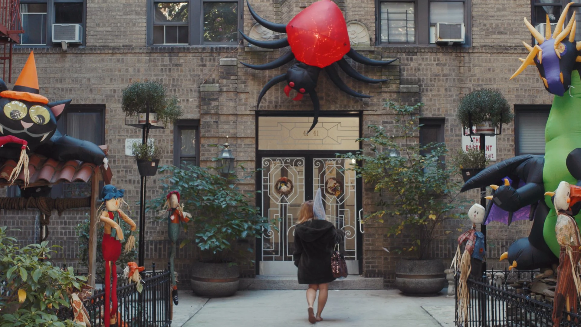 Woman entering apartment building with halloween decorations