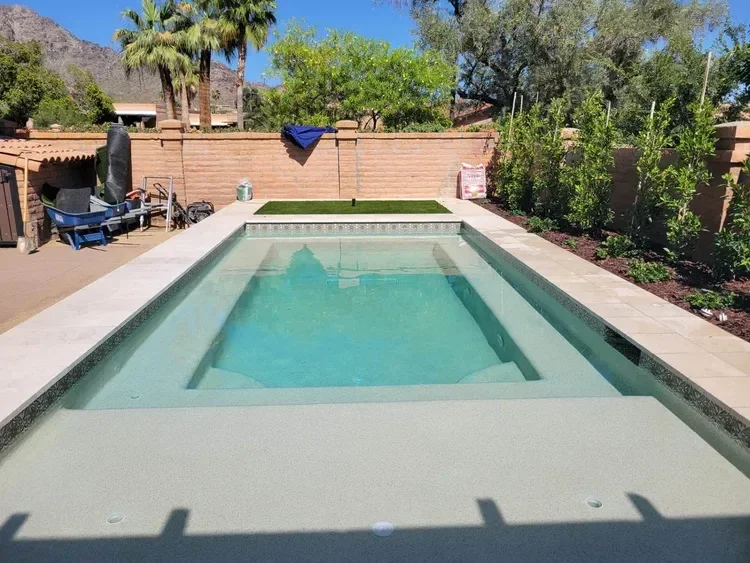 Backyard with swimming pool, patio, and garden; trees and mountains in the background.