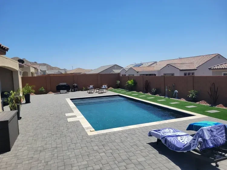 Residential backyard with swimming pool, patio, and barbecue grills.