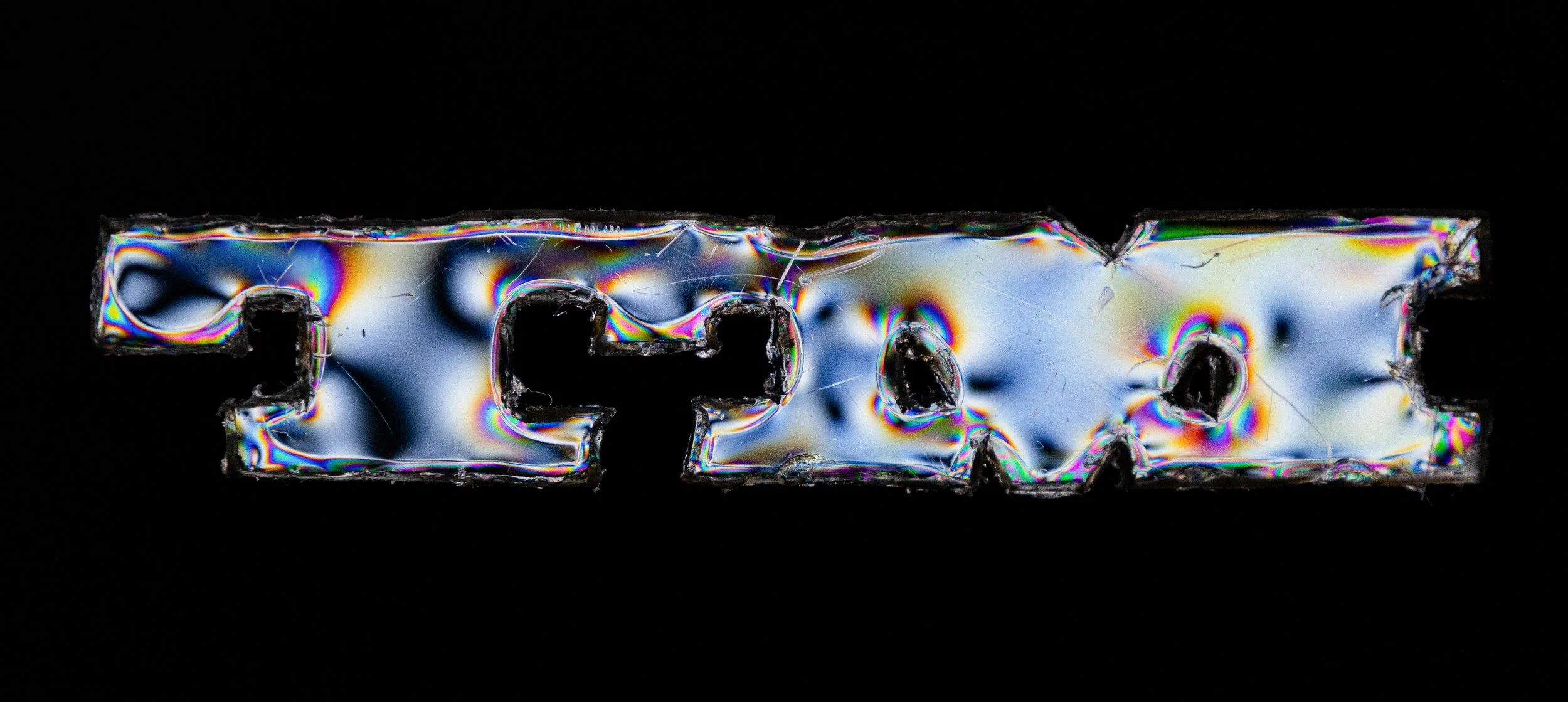 Close-up of a metallic screw with iridescent rainbow colors on a black background.