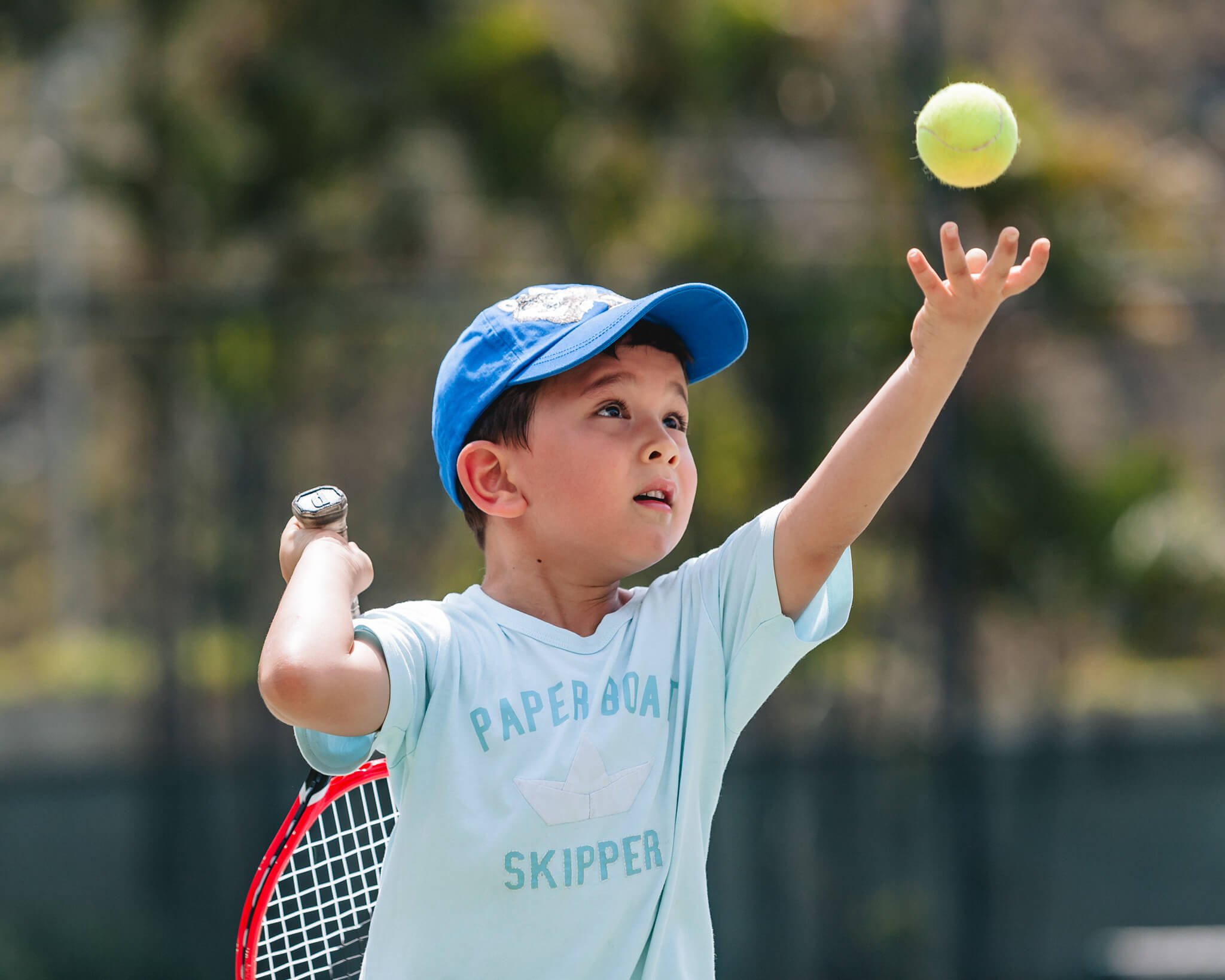 Boy serves at tennis during a documentary style photo session in Hong Kong