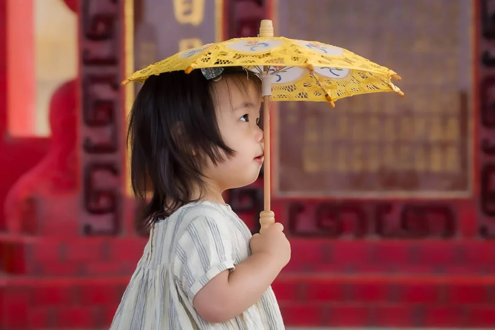 A kid plays with a parasol during a Hong Kong family photoshoot at Repulse Bay