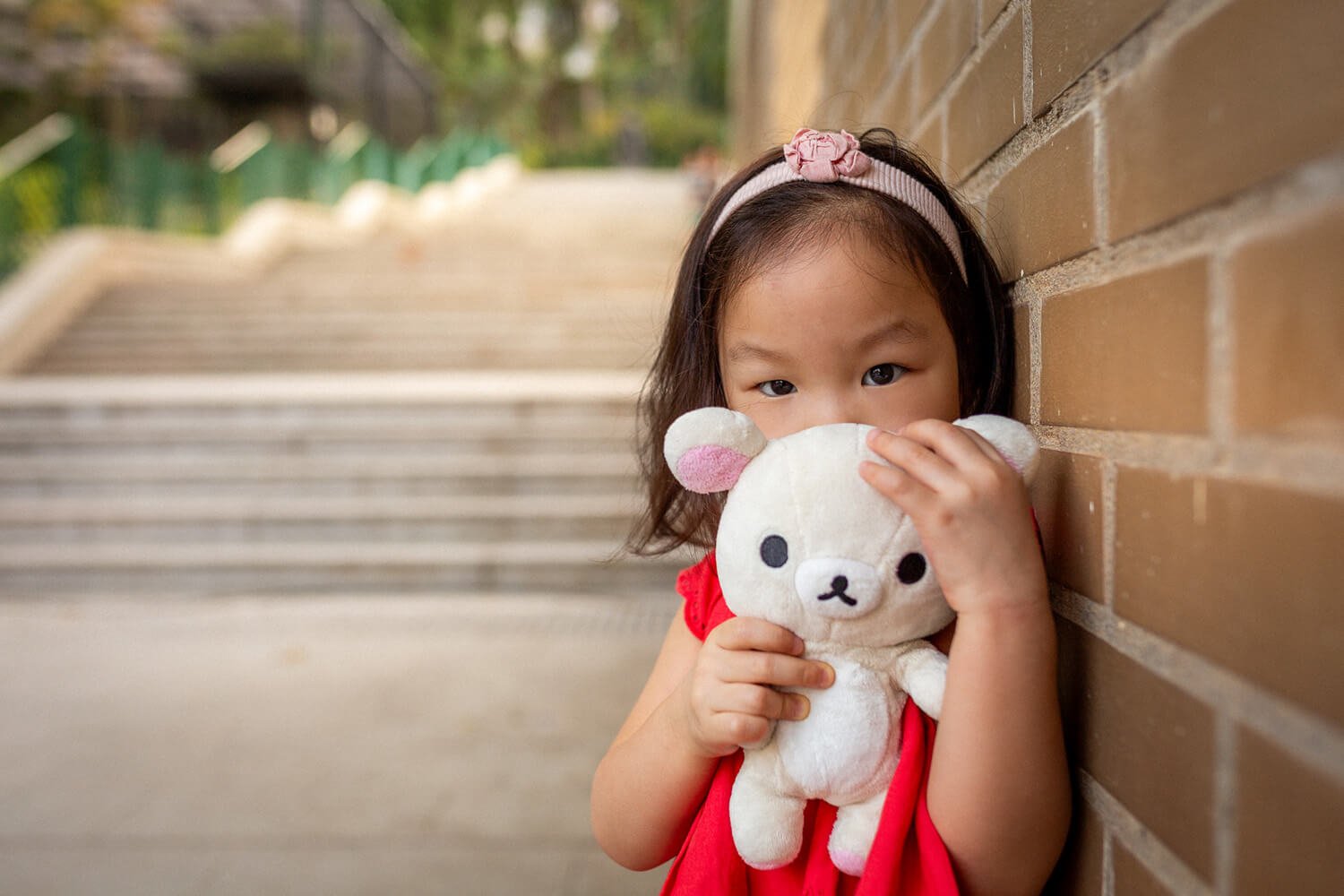 Girl holds her teddy bear at a lifestyle family photoshoot at The Botanical Gardens in Hong Kong