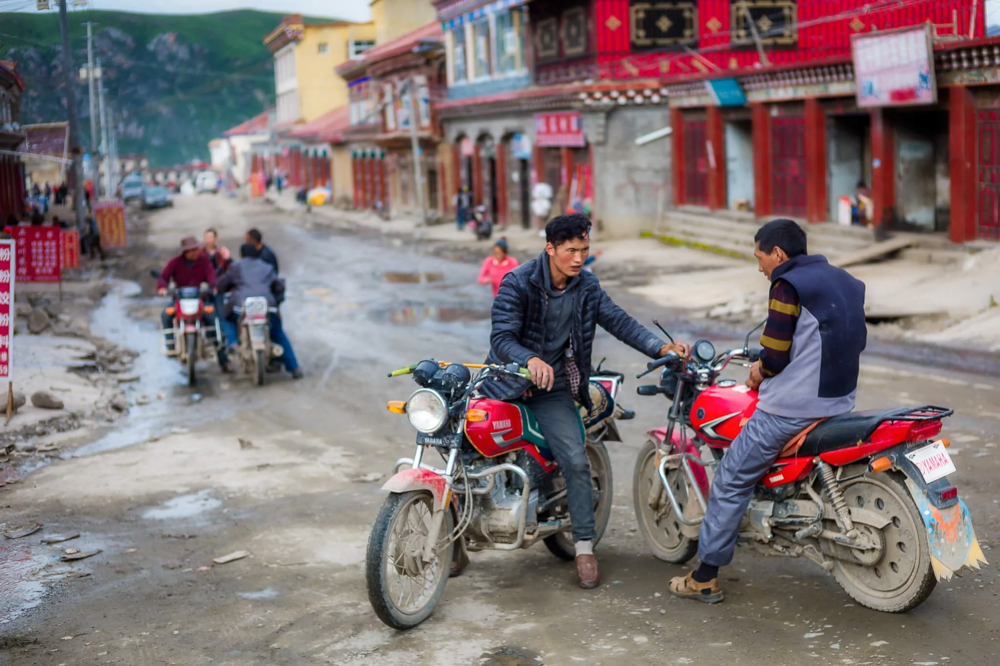 Two Tibetan men on motorcycles, Garzê, China — travel photo by HK photographer