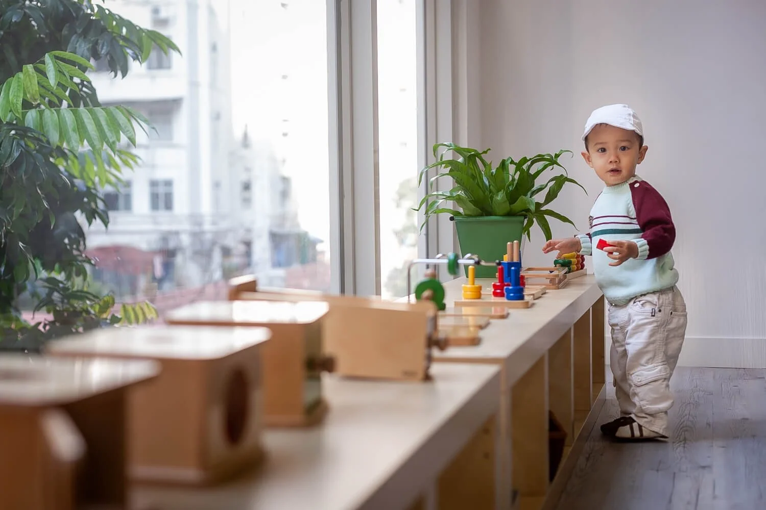 Candid photography of a boy focused on sensorial Montessori work in a Hong Kong classroom.