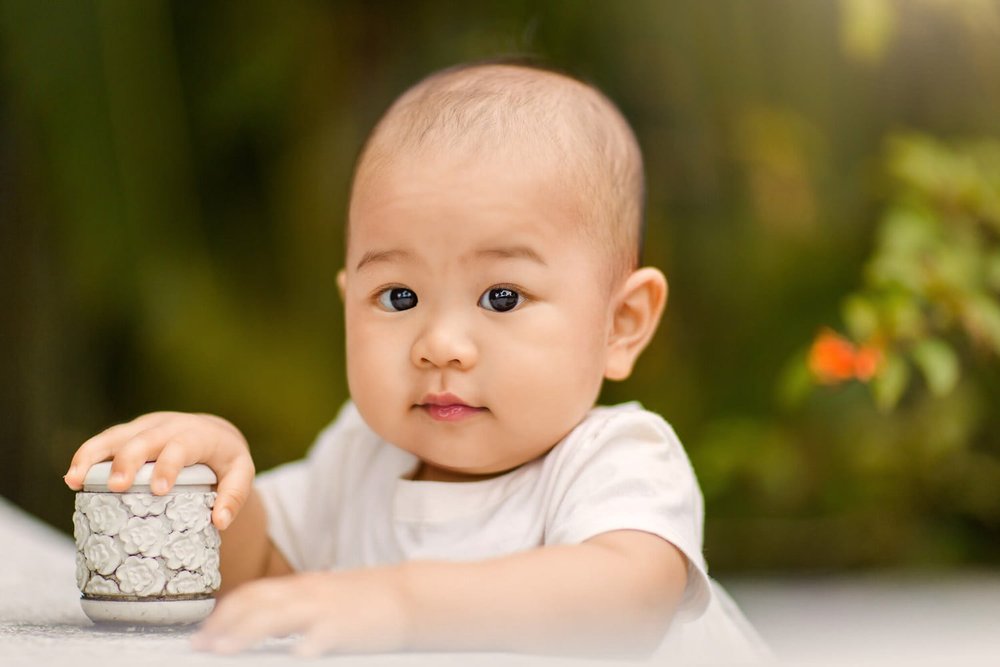 At Sun Yat Sen Park a one-year girl leans on a Chinese bench