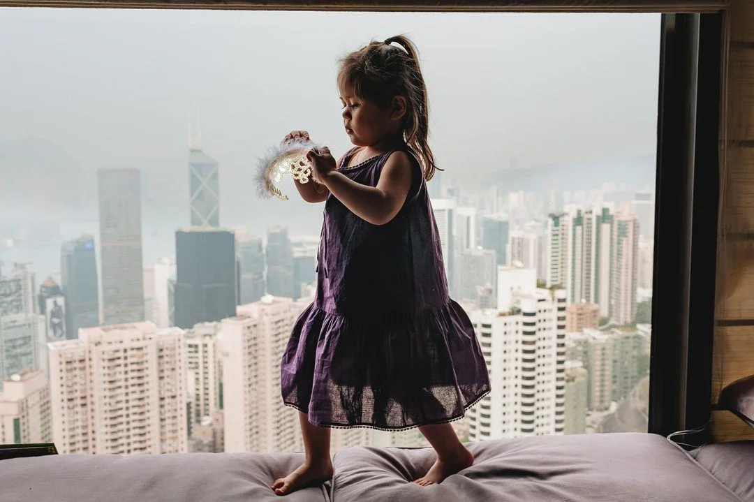 Girl playing in her bedroom at The Peak with a view of the city below