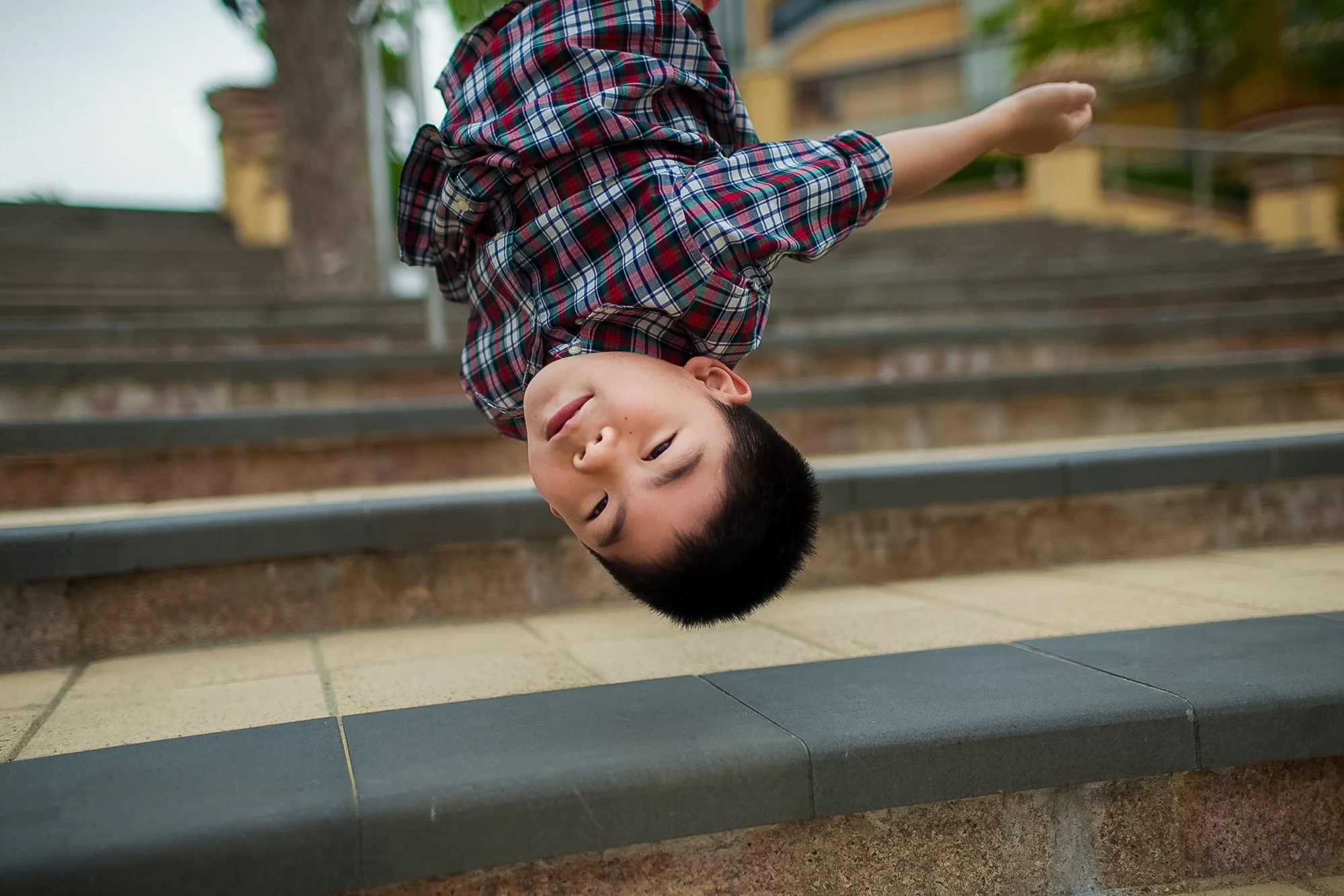 Kid hangs upside down during a photo session with Ian Taylor in Discovery Bay Hong Kong
