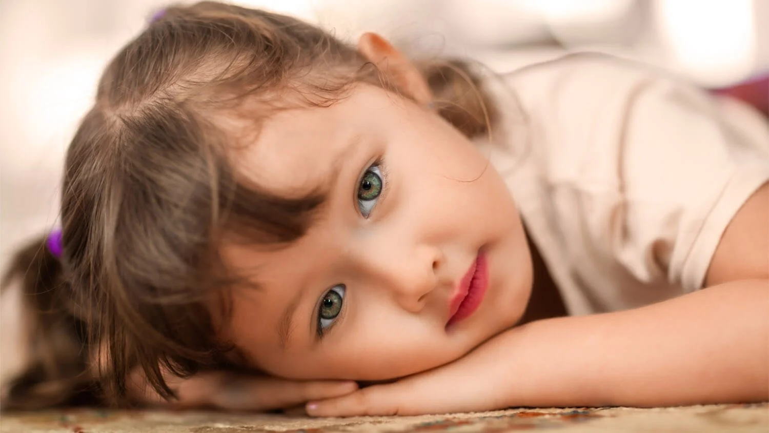 Girl lays on carpet and has her photo taken at home