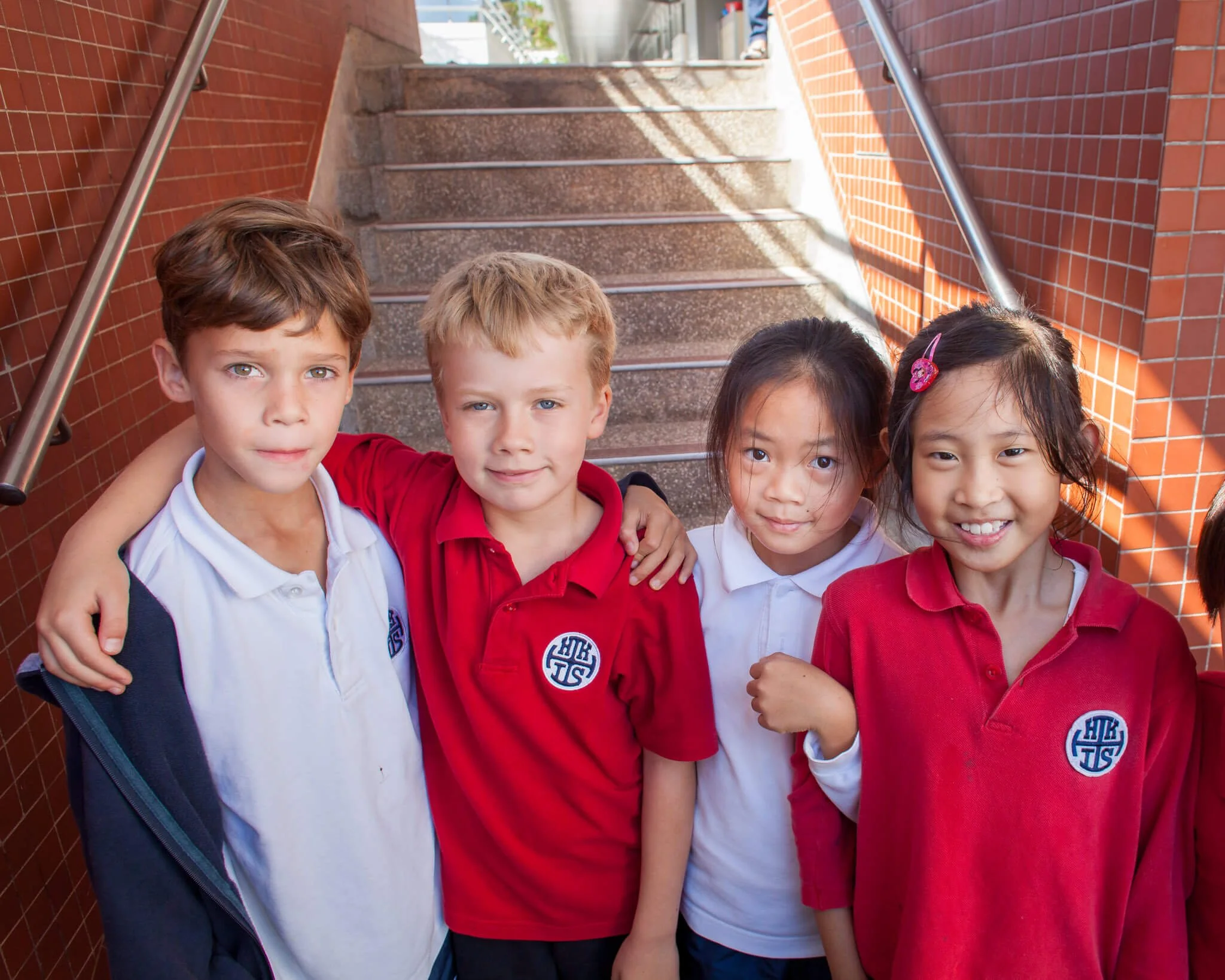 At HKIS four kids stop at the bottom of the stairs to pose for a photo.