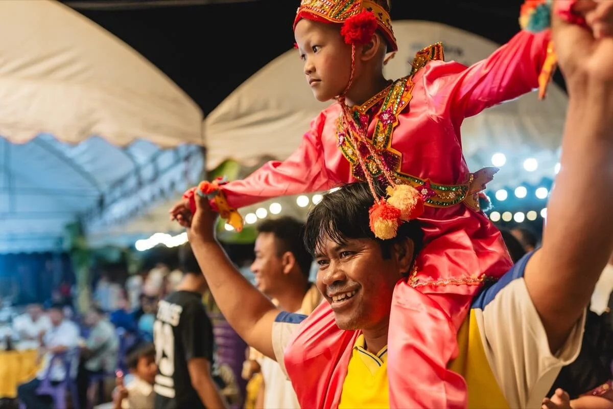 Boy in costume carried on man's shoulders