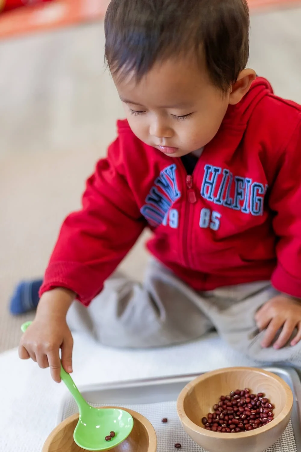 Boy practicing fine motor skills with Montessori materials; documentary school photography by Ian Taylor