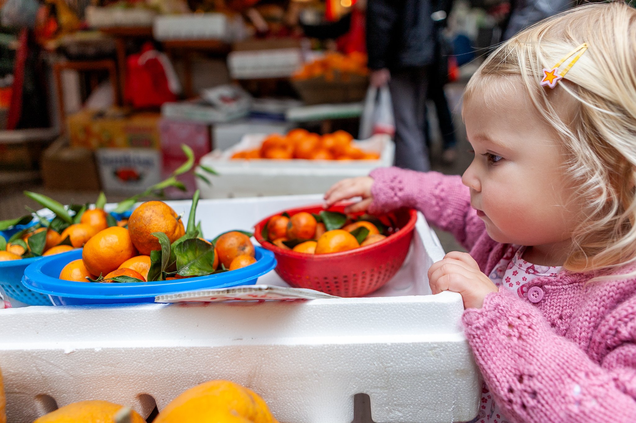Ian Taylor Photography : Girl looks at oranges in the lanes of Central HK