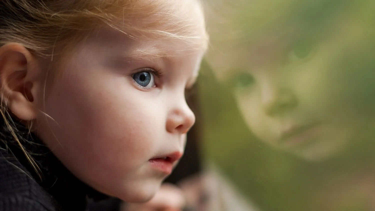 Girl's reflection in a window during a quiet moment.