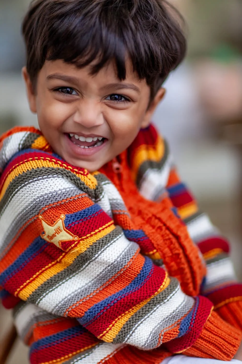 Boy laughs unselfconsciously during school photography session at a Hong Kong Montessori school"