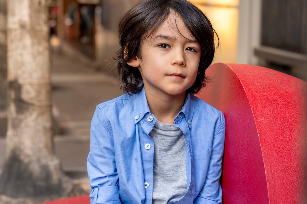 Boy poses for a photo on a red bench in Sheung Wan