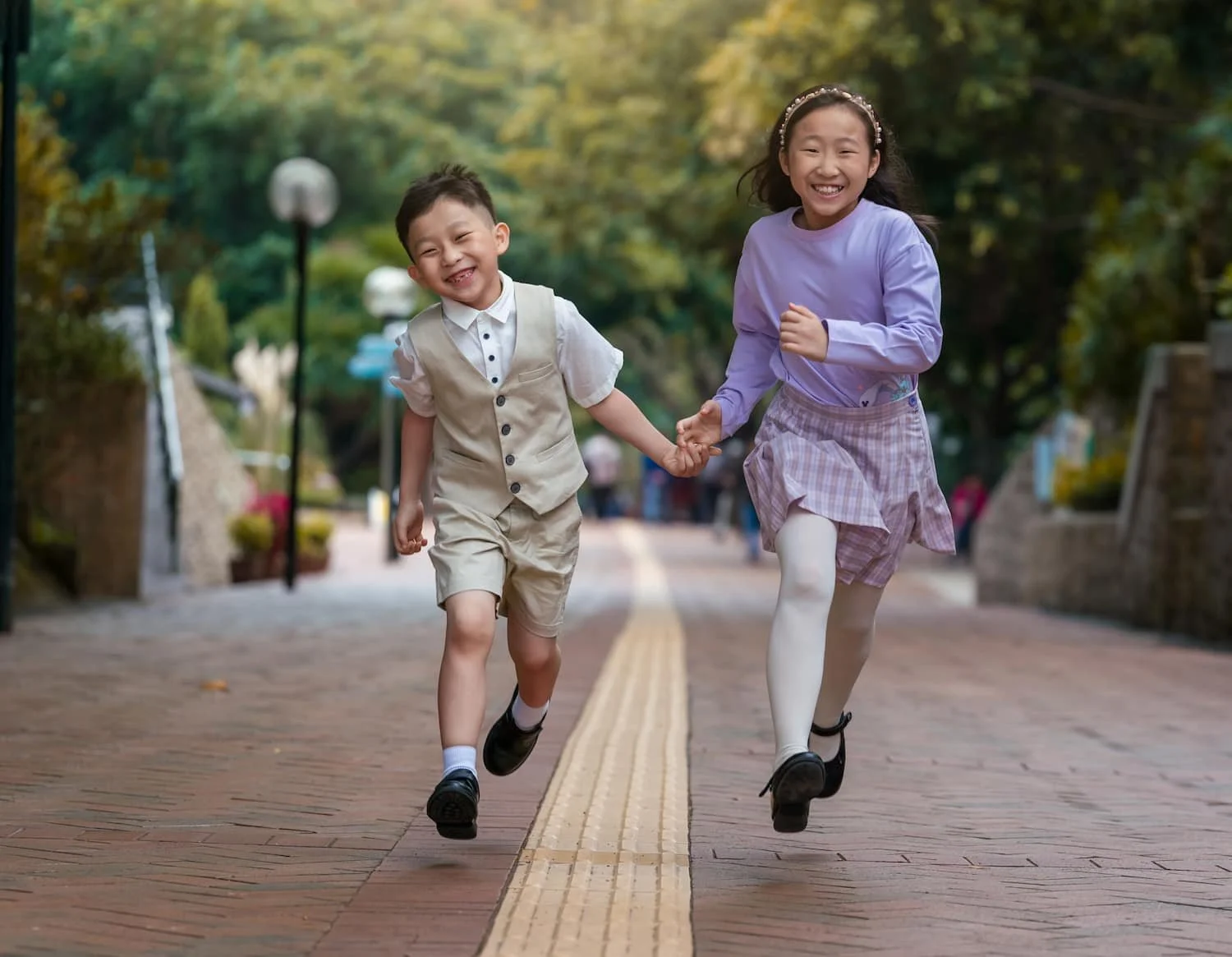 Siblings run during a Kowloon Park kids photography session by Ian Taylor