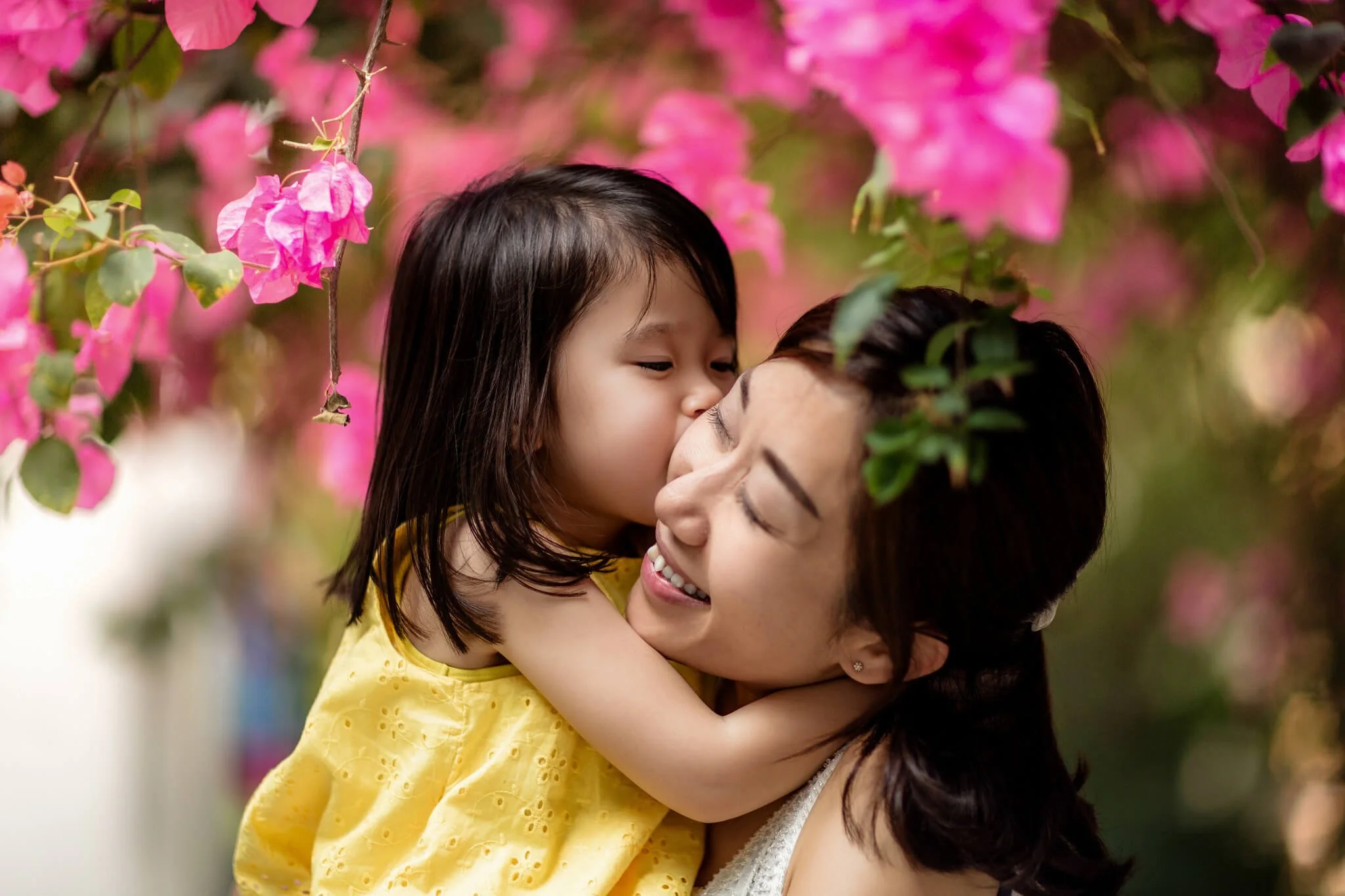 Natural family photography in Hong Kong: A candid portrait of a mother and daughter laughing together outdoors by Ian Taylor Photography.