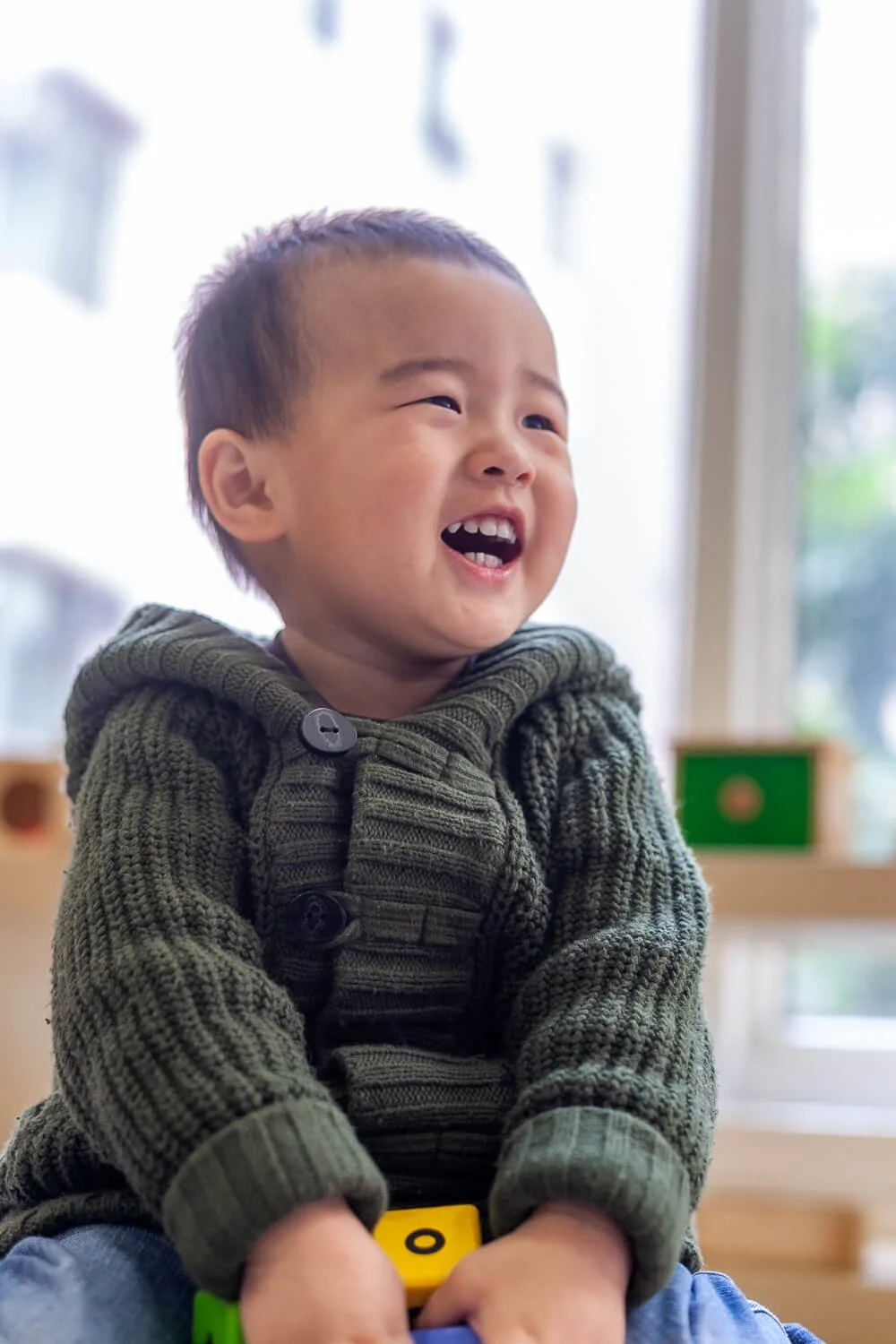 A boy laughs while playing with blocks, by school photographer Ian Taylor