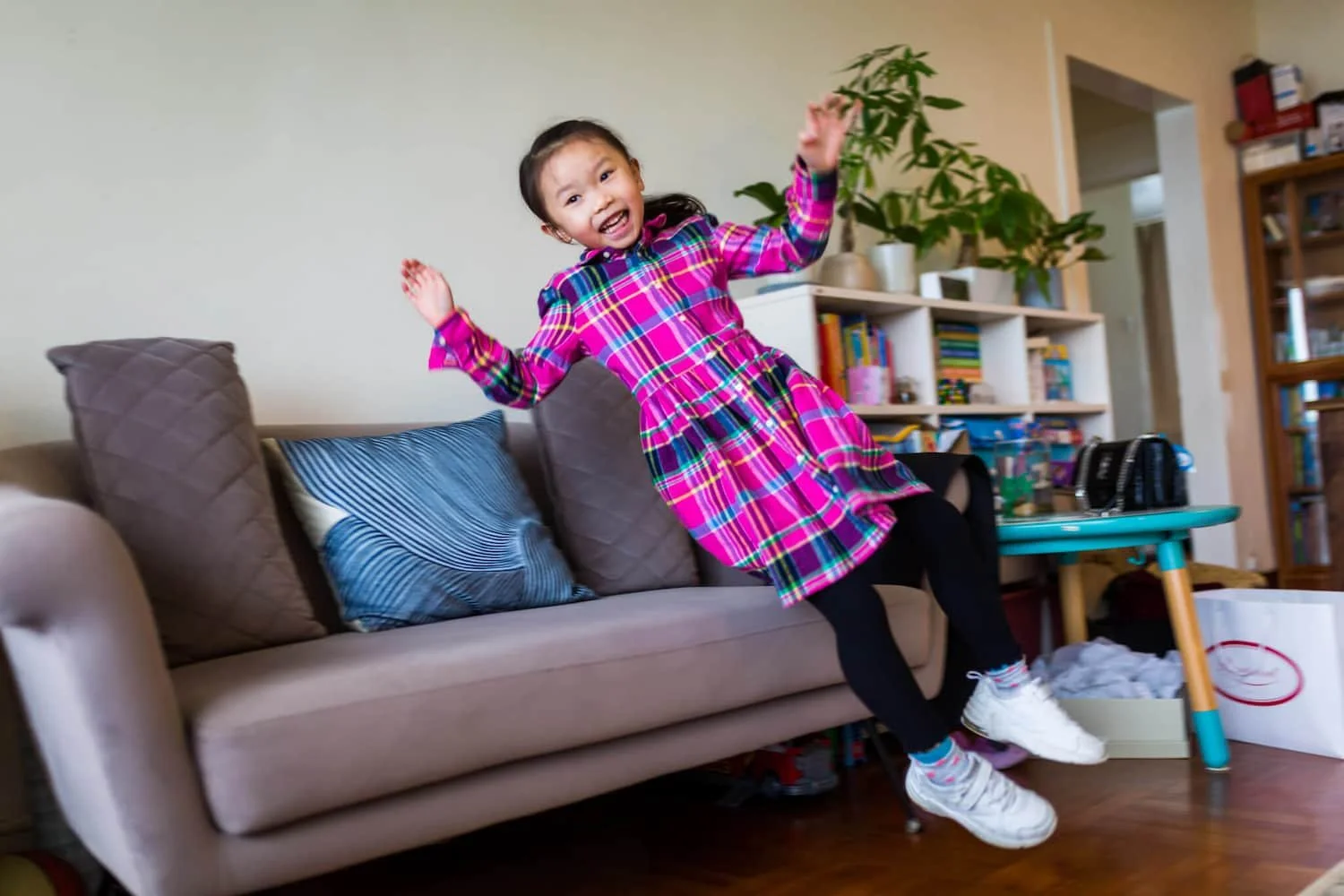Girl jumps onto the sofa during a natural kids' portrait session in Clearwater Bay, HK