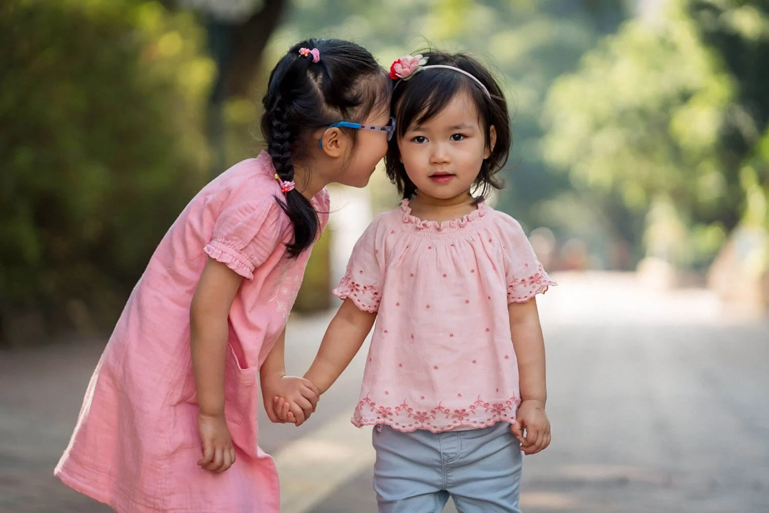 Two sisters holding hands outdoors in Kowloon Park Hong Kong