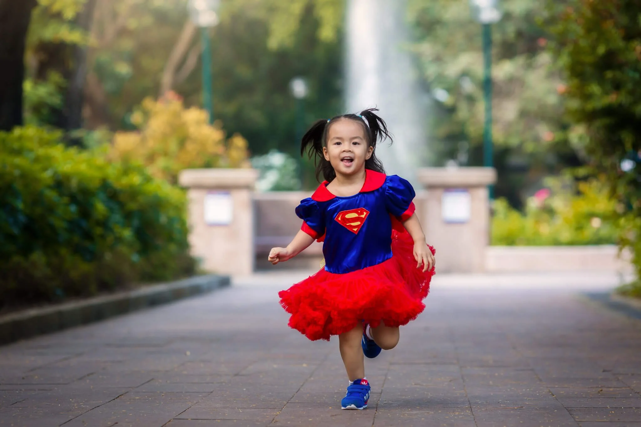 Kid in a Superman costume runs in Kowloon Park Hong Kong during a natural documentary photo session