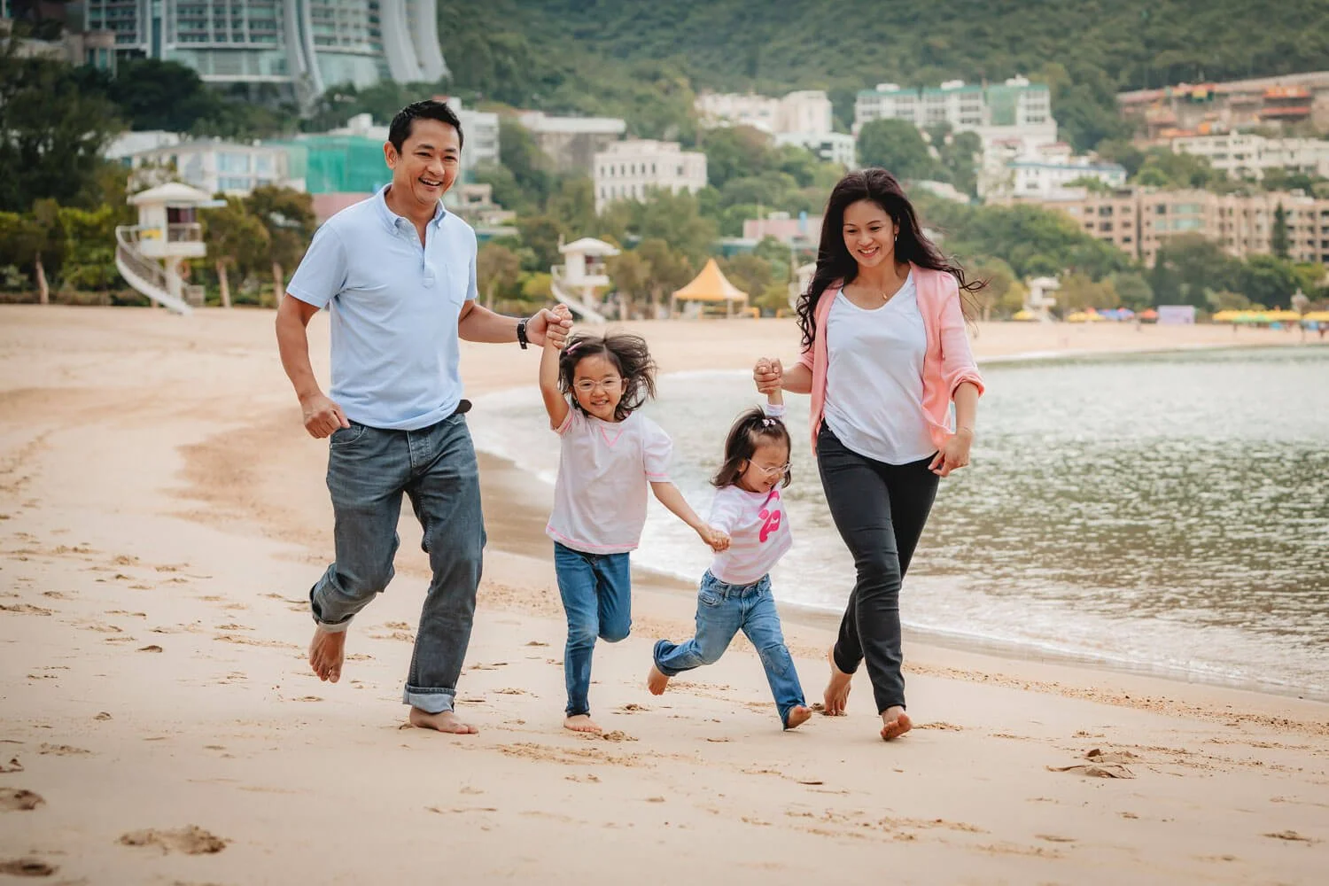 Family of four running down Repulse Bay Beach, Hong Kong