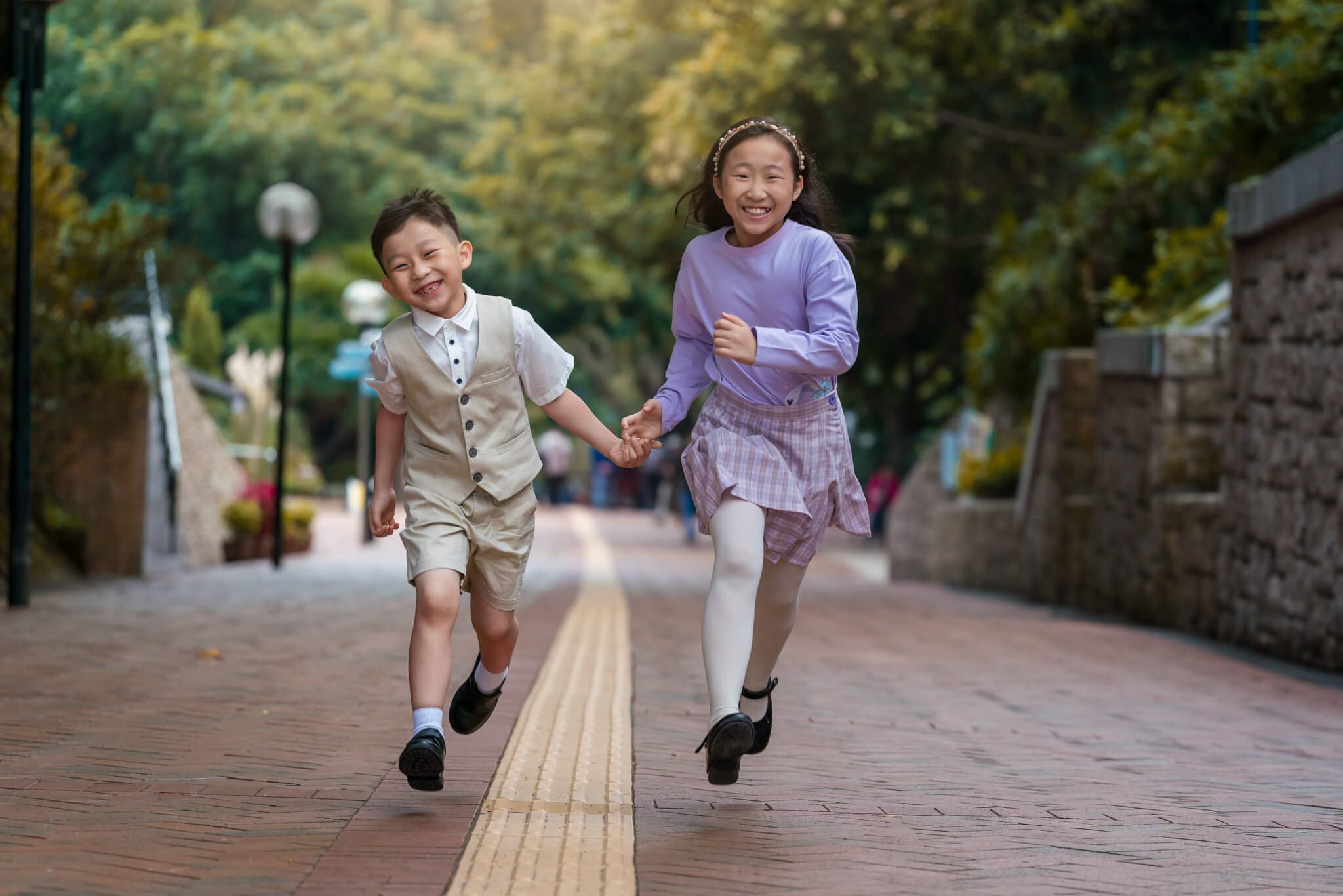 Siblings run in Kowloon Park for family photos