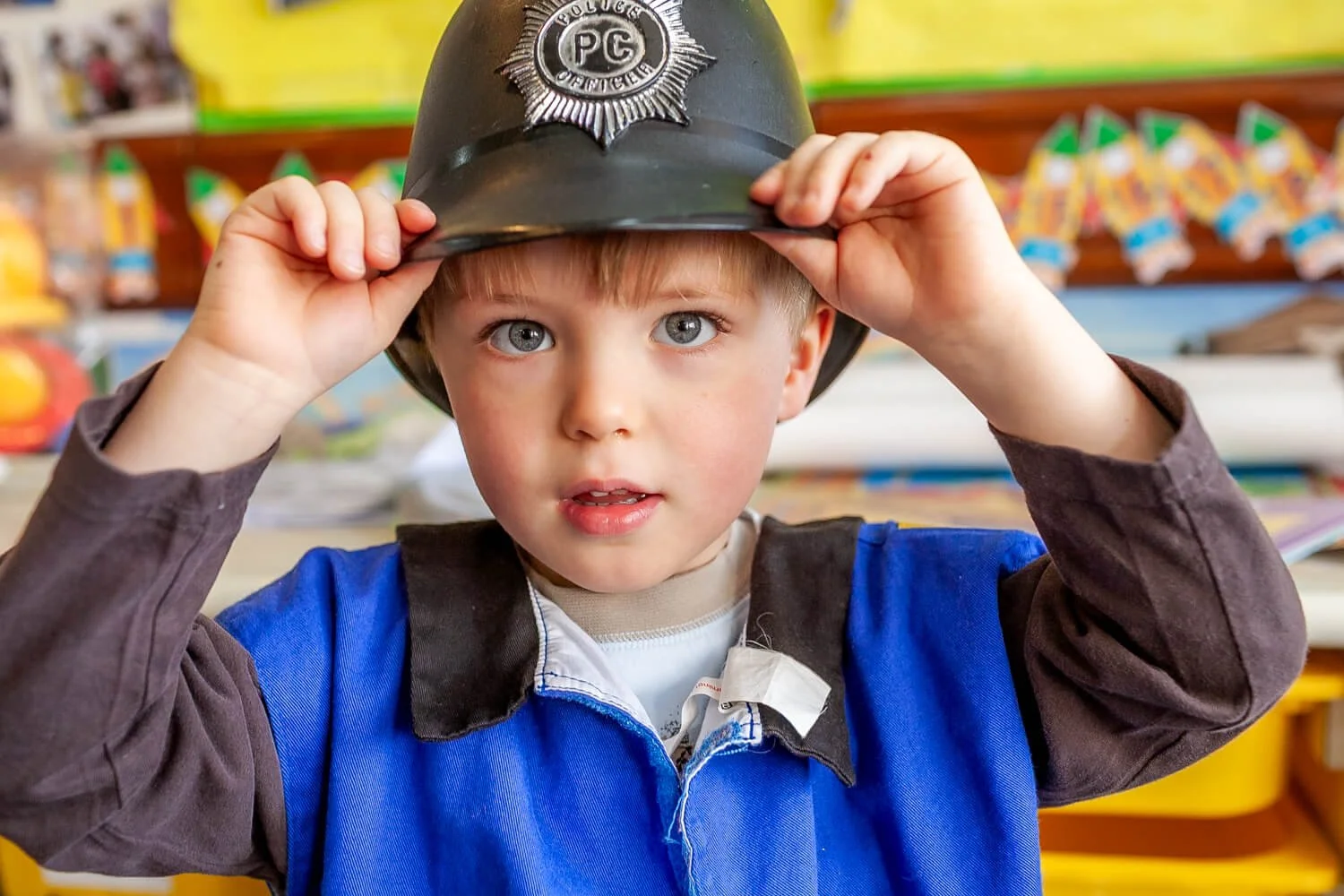 A boy wears a British bobby's hat at a Hong Kong school