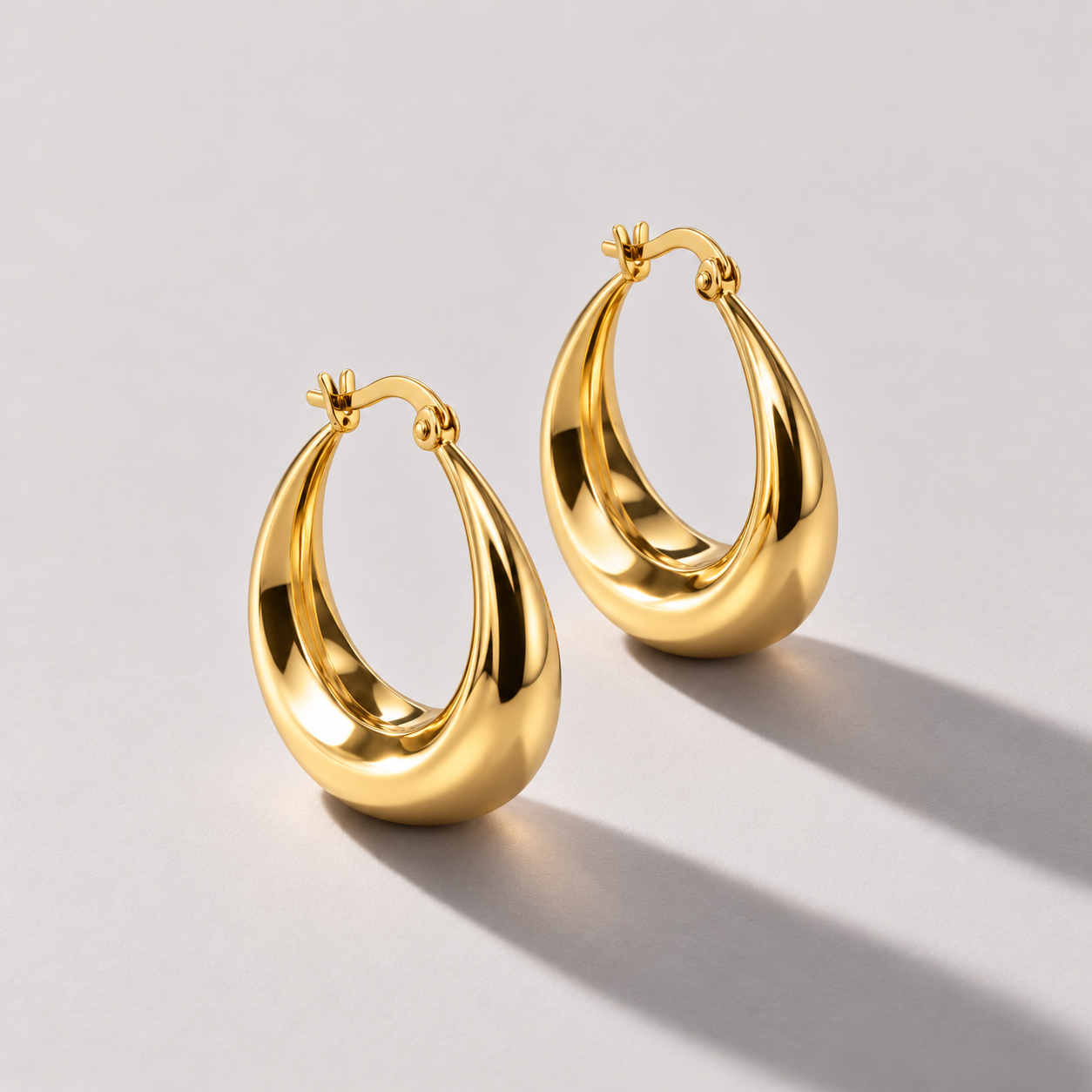 Tapered gold crescent hoop earrings.png