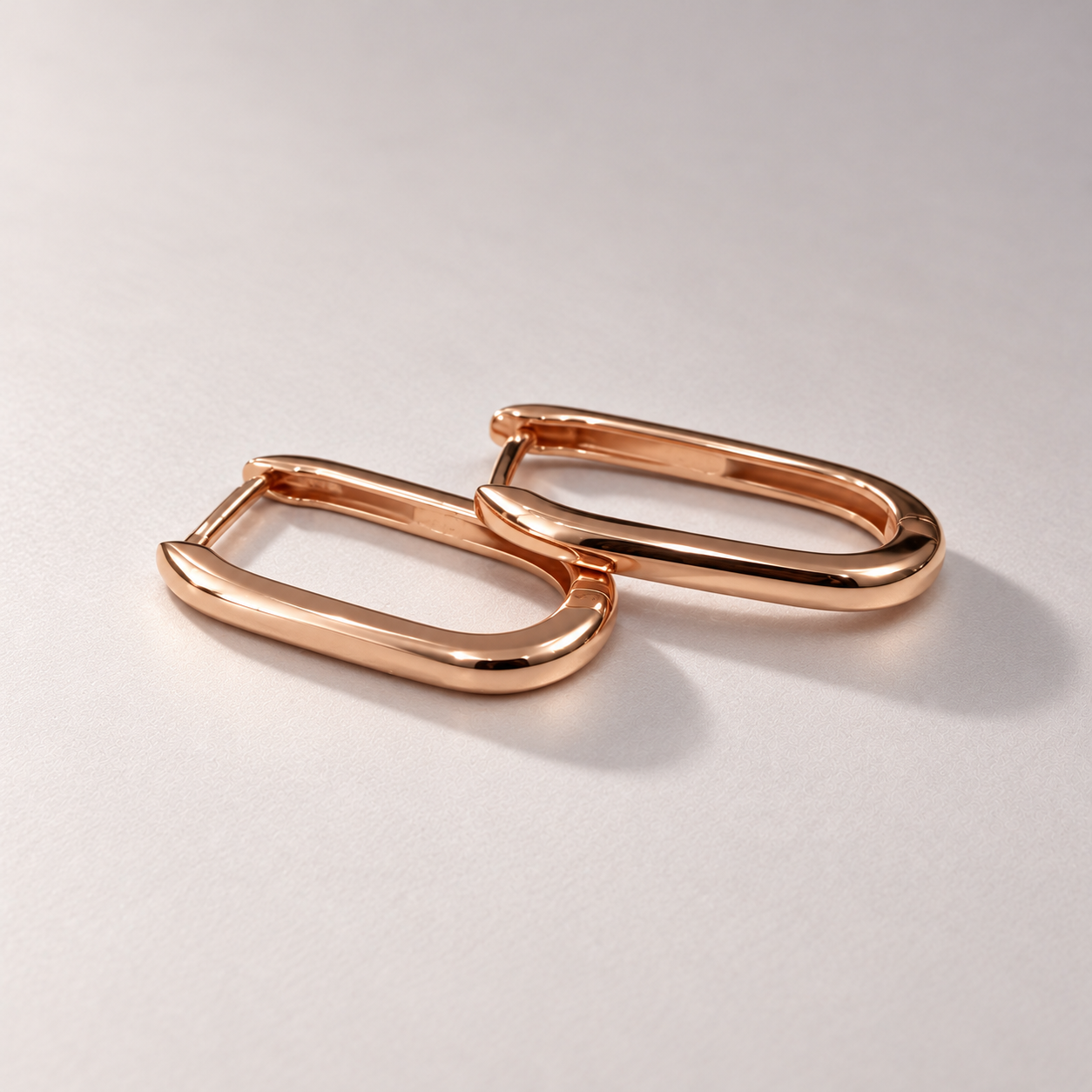 Overlapping polished rose gold hoops on matte grey-1.png