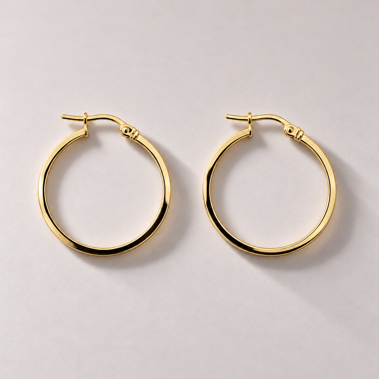 Gold hoop earrings on a mauve-gray surface-2.png