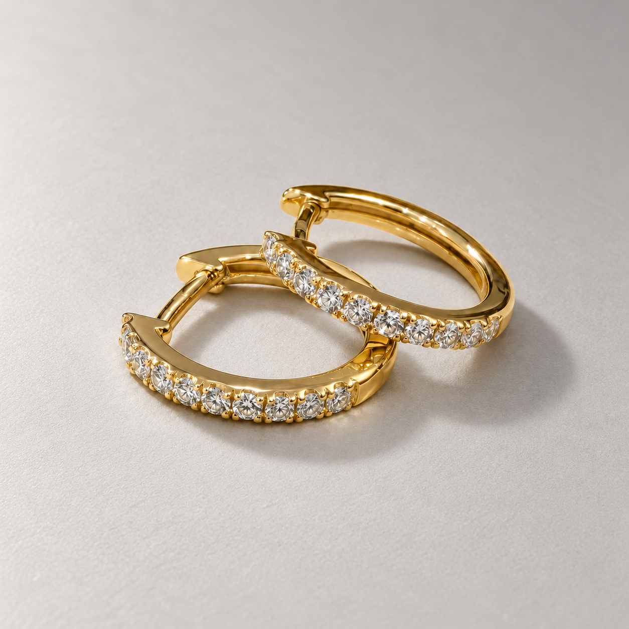 Overlapping gold diamond hoops on matte grey.png