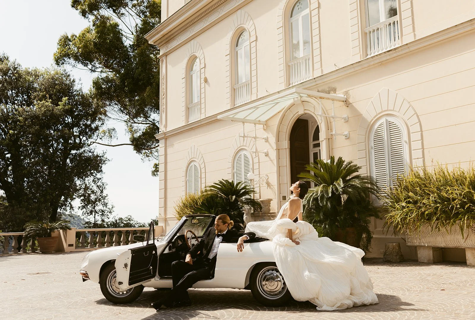 Bride and groom in a vintage car in front of an Italy wedding venue: Villa Astor