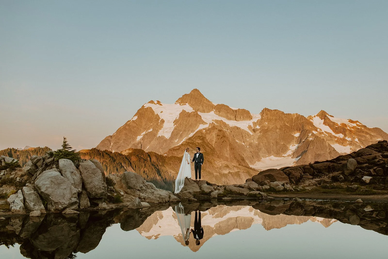Bride and groom stand on rocks above Picture Lake during their North Cascades Elopement