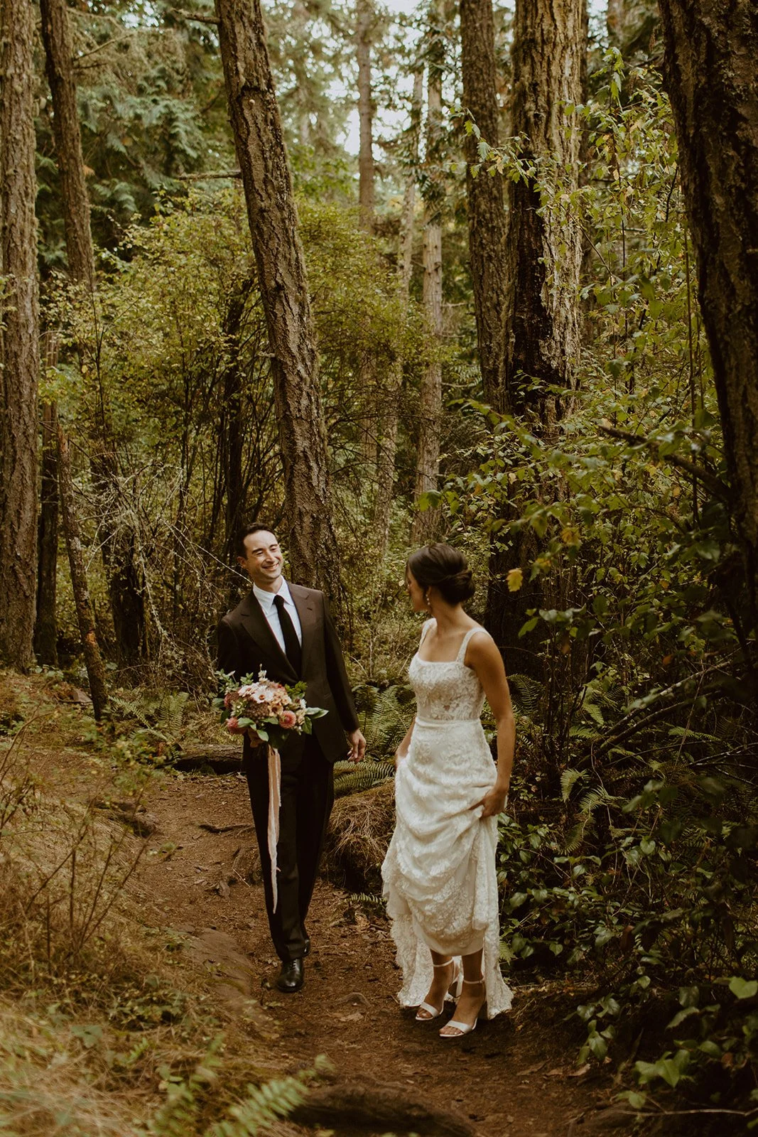 Bride and groom hike through the forest on Orcas Island