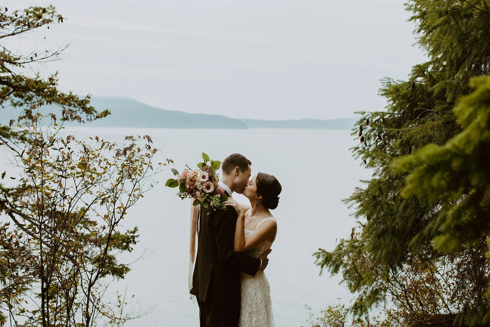 Bride and groom kiss with the Puget Sound in the backdrop