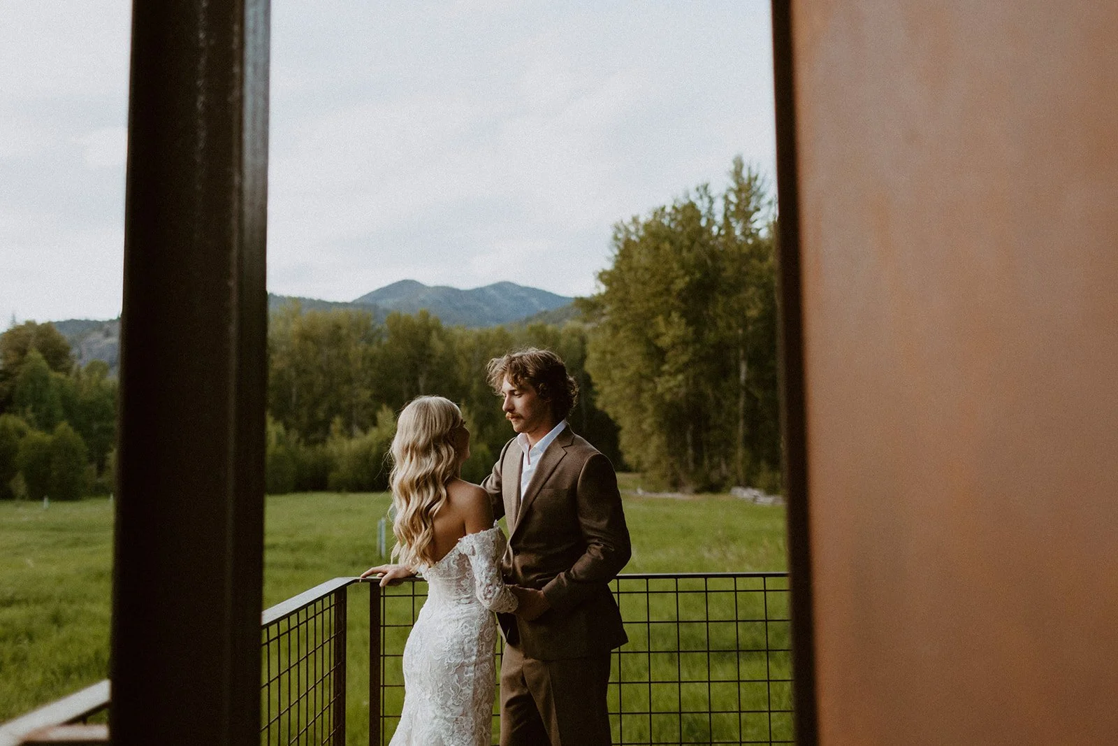 Bride and groom stand on a porch of a mountain home in Washington State