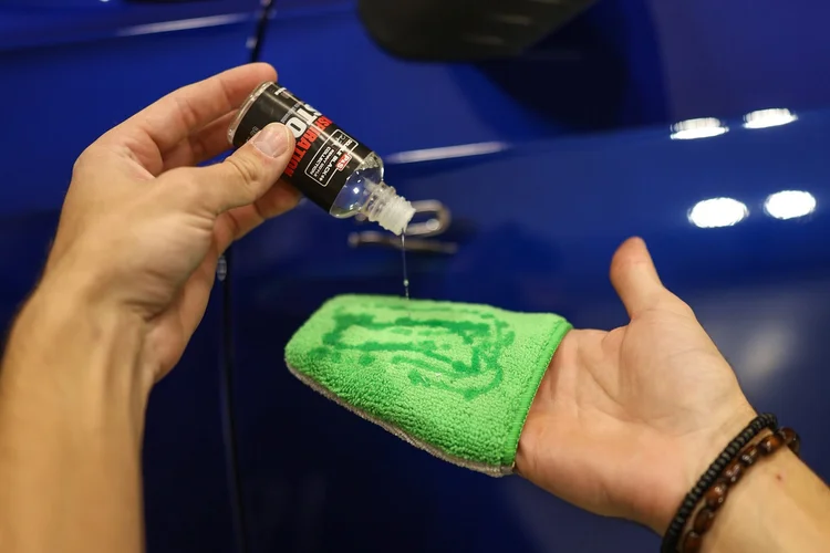 Ceramic coating decanted onto an applicator block over a deep blue painted panel at Ascension Automotive
