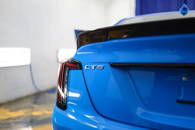 Close crop of a blue Cadillac rear quarter panel showing depth in the paint after paint correction at Ascension Automotive