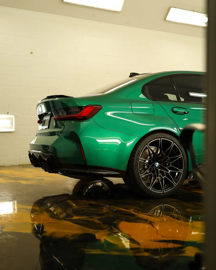 Green BMW M3 under studio lighting on the reflective floor after paint correction at Ascension Automotive