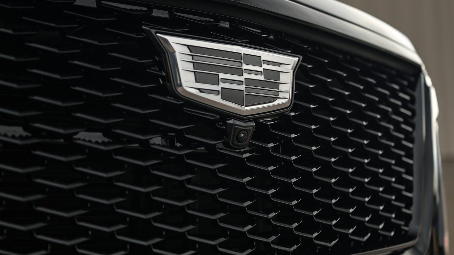 Close view of a black Cadillac Escalade grille and chrome crest after auto detailing at Ascension Automotive in Milford, Michigan