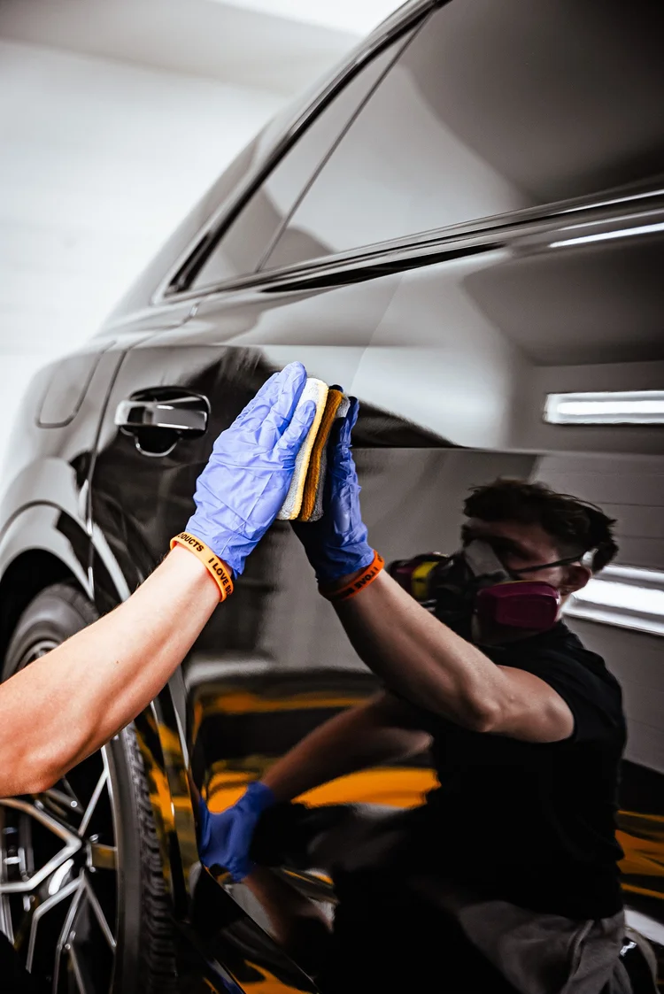 Gloved technician pressing a coating applicator onto glossy black paint on an Audi Q8 at Ascension Automotive