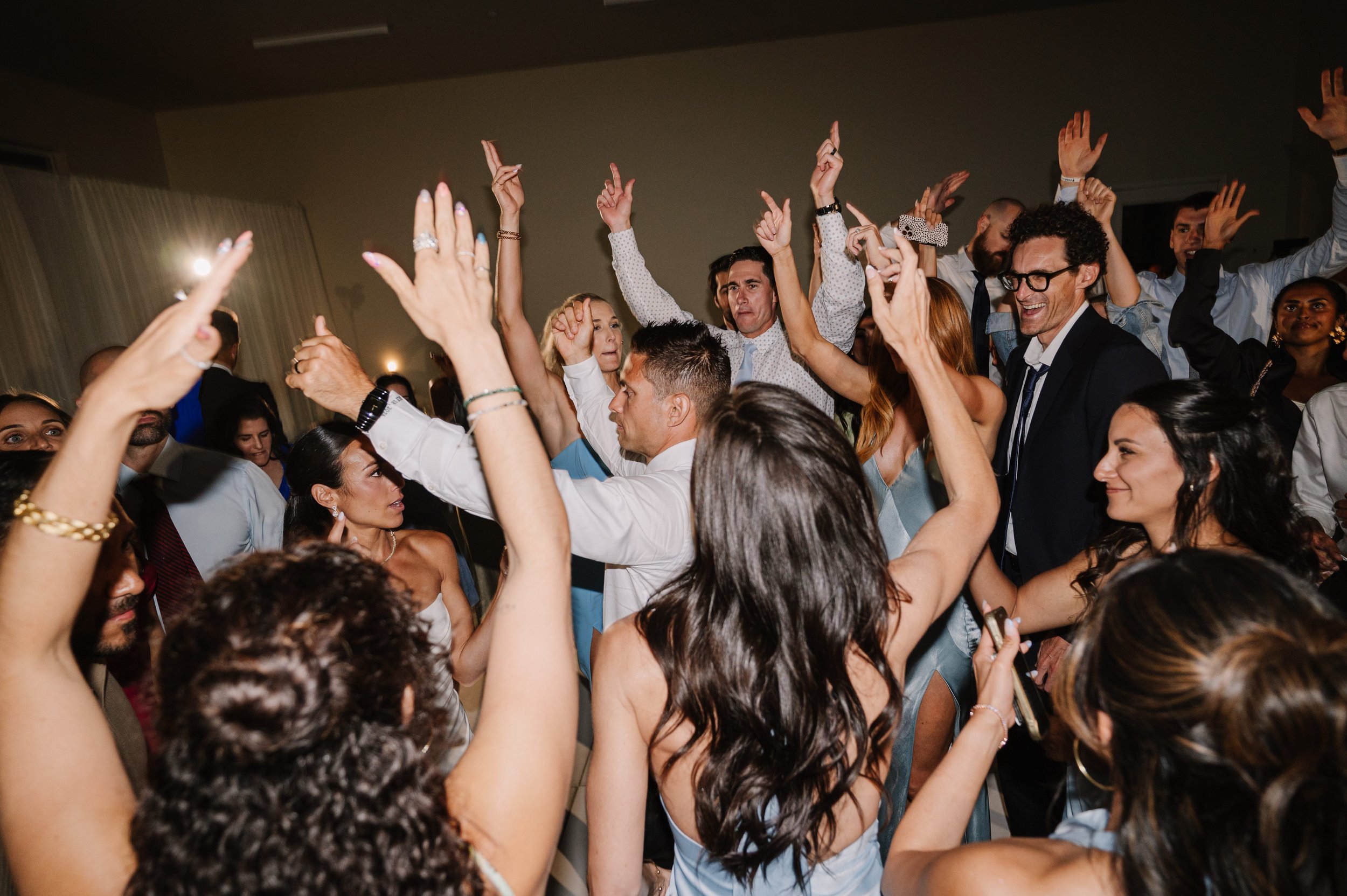 Photo Credit: Nikkels Photography, Private Estate, Atascadero Wedding (The newlywed couple is at the center of their dance floor. The groom and many guests have their hands in the air. It's clear this is a highlight of everyone's night!)