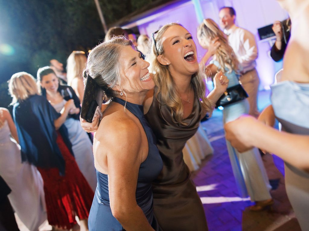 Photo Credit: Ashley Rae Collective, Biddle Ranch Vineyard, San Luis Obispo Wedding (Two ladies dance side by side and are singing along to a song. Behind them many other wedding guests are seen enjoying the party!)