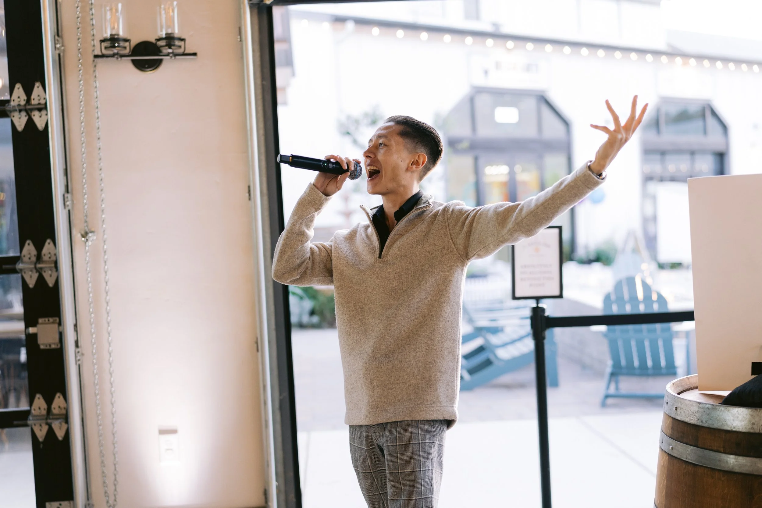 MC Steven standing in an event space, using a wireless handheld microphone, and leading with energy.