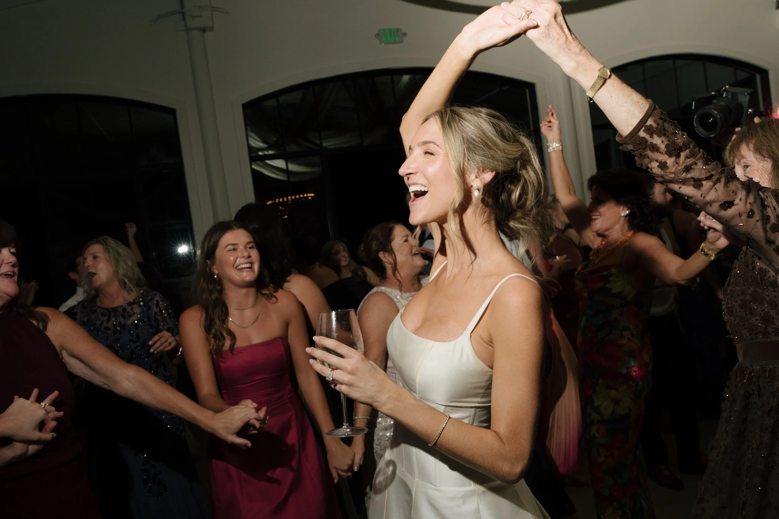 Photo Credit: Catherine Marie Taylor, Greengate Ranch, San Luis Obispo Wedding (A bride is dancing on her wedding night. One of her guests is twirling her. Many of her friends are also dancing and cheering them on.)