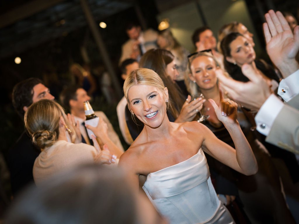 Photo Credit: Ashley Rae Collective, Biddle Ranch Vineyard, San Luis Obispo Wedding (A bride smiles at one of her guests on the dance floor. We can see several of her friends and family in the background, also enjoying the party.)