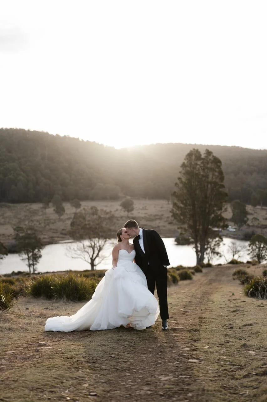 Bride and groom kissing on a dirt track overlooking the lake at Currawong Lakes, Lake Leake, North East Tasmania