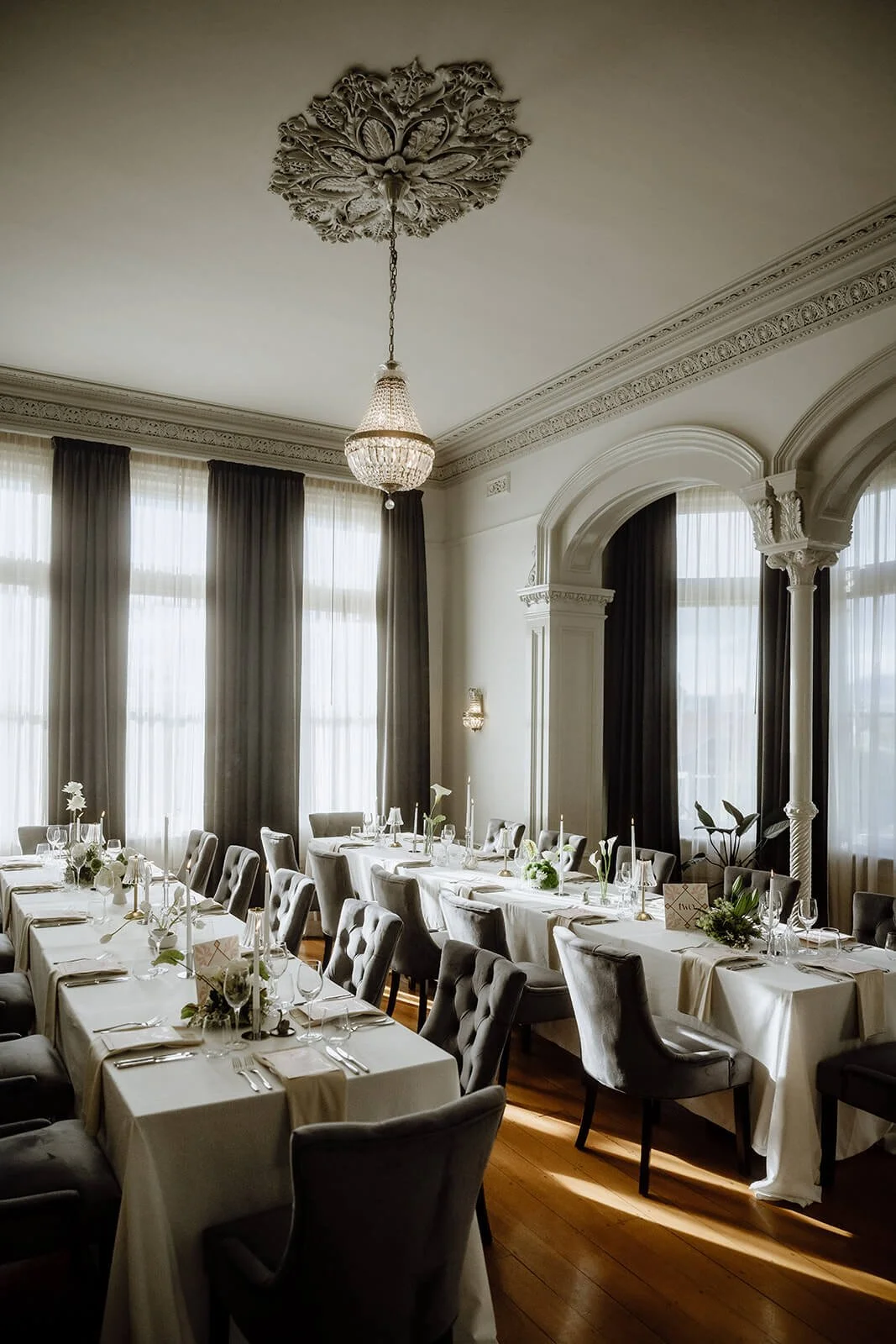 Elegant heritage dining room at Maylands Lodge set for a wedding reception, ornate ceiling rose, crystal chandelier and arched windows